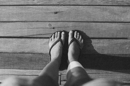 a person standing on a wooden floor with their feet crossed