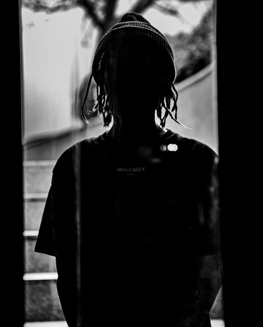 a man with dreadlocks standing in front of a window