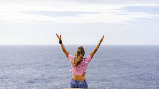 a woman with her arms raised in front of a body of water