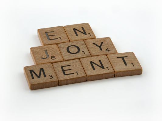 a scrabble of wooden blocks spelling the words enjoy joy, joy, and