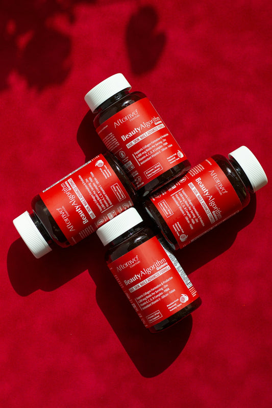 Three bottles of red liquid sitting on top of a red surface