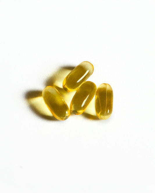 Four yellow capsules sit on a white surface.