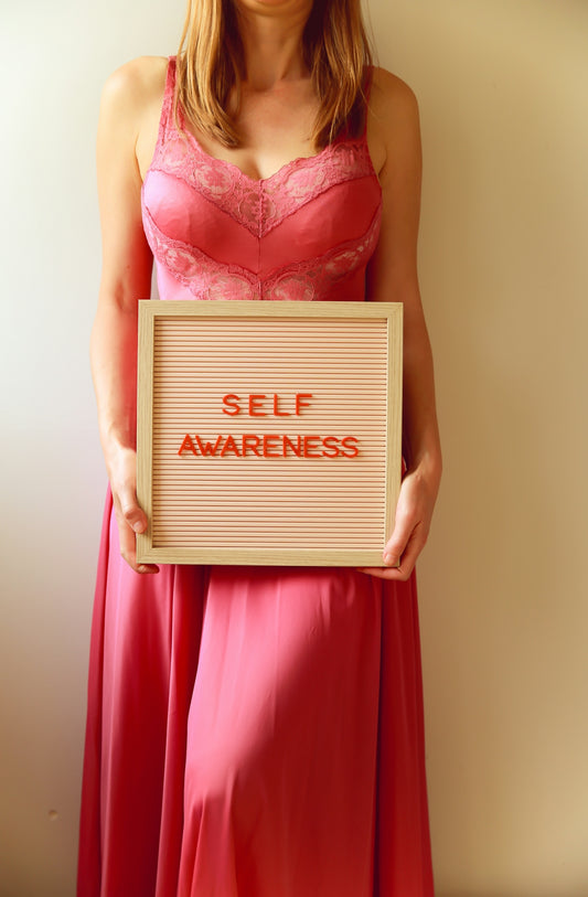 Woman holds a sign that says self awareness.