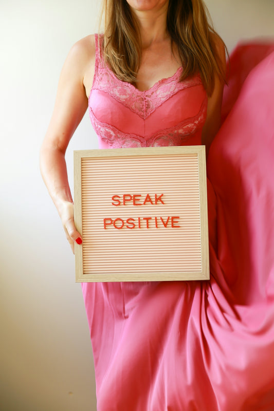 A woman holds a sign, speak positive.