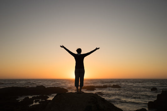 Silhouette of a person with arms raised at sunset.