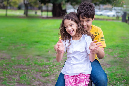 boy and girl standing on grass while smiling