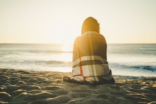 woman sitting on brown sand covered with blanket