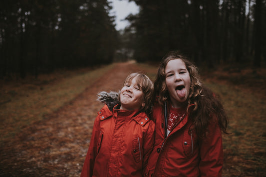 smiling girl standing beside another girl showing up her tongue