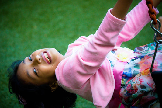 a little girl playing on a swing set