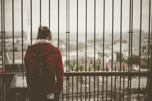 woman in red hoodie standing in front of metal balustrade