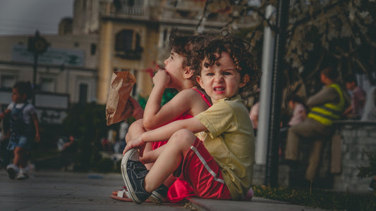 girl's yellow top and red shorts sitting on concrete pavement outdoor