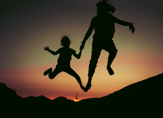silhouette of two children jumps