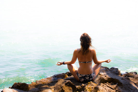 woman in black and white bikini standing on rock near sea during daytime