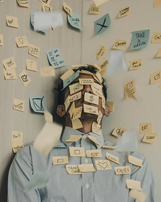 man covered in sticky notes at office desk