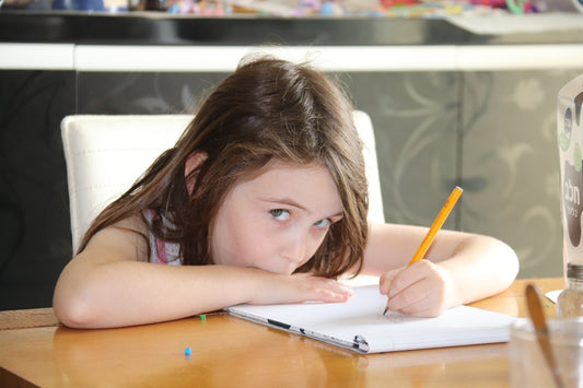 girl in pink tank top writing on notebook