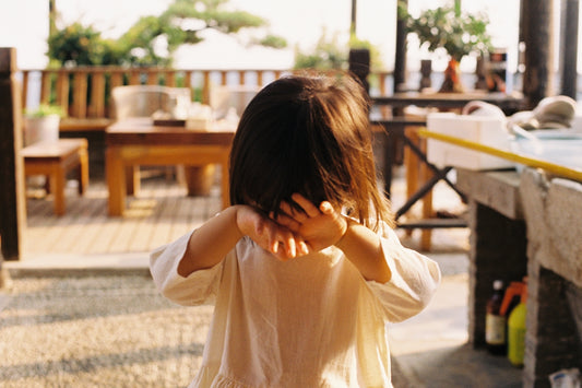 girl in yellow long sleeve shirt covering her face with her hands