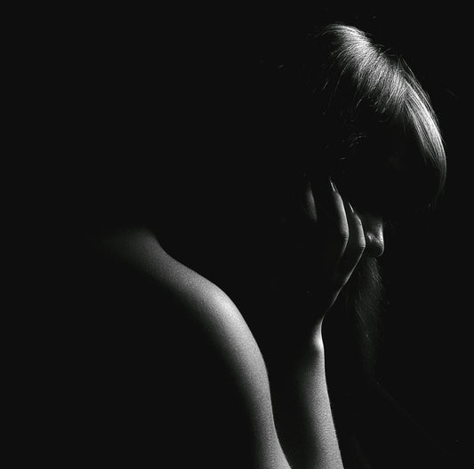 grayscale photo of woman covering her face with her hand