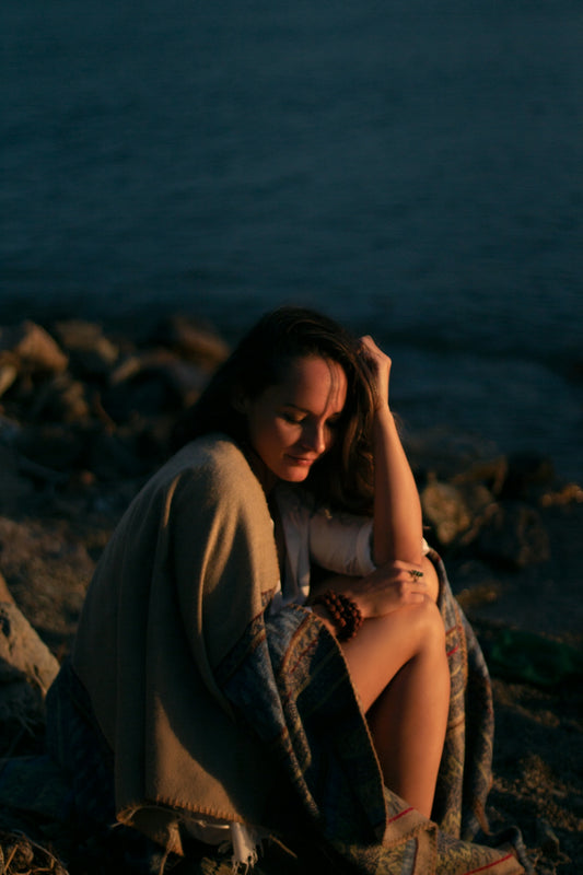 woman in white shirt sitting on rock near body of water during daytime