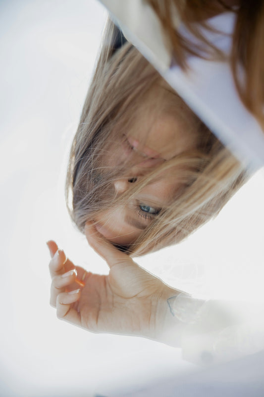 woman in white long sleeve shirt covering her face with her hand