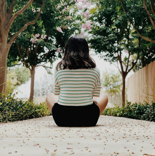 woman in white and black stripe shirt sitting on ground during daytime