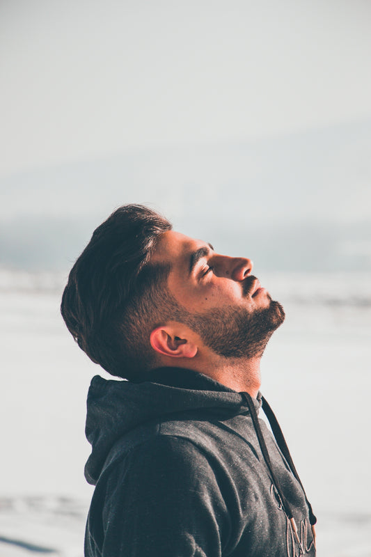 man in black hoodie looking at the sea during daytime