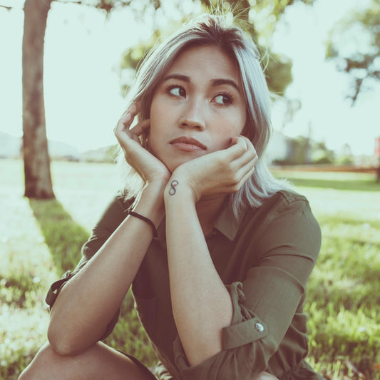 woman in green button up shirt covering her face with her hand