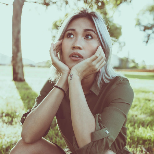woman in brown leather jacket sitting on green grass field during daytime