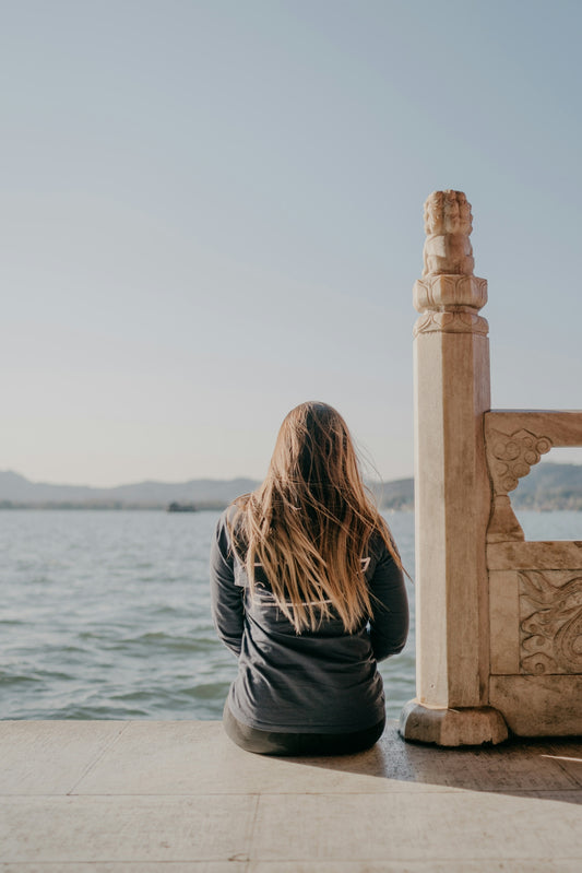 woman in gray shirt standing near body of water during daytime