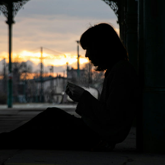 woman in white long sleeve shirt sitting on floor during sunset
