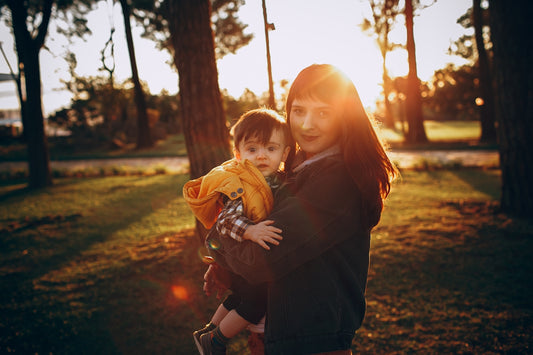 woman in black long sleeve shirt carrying girl in brown jacket