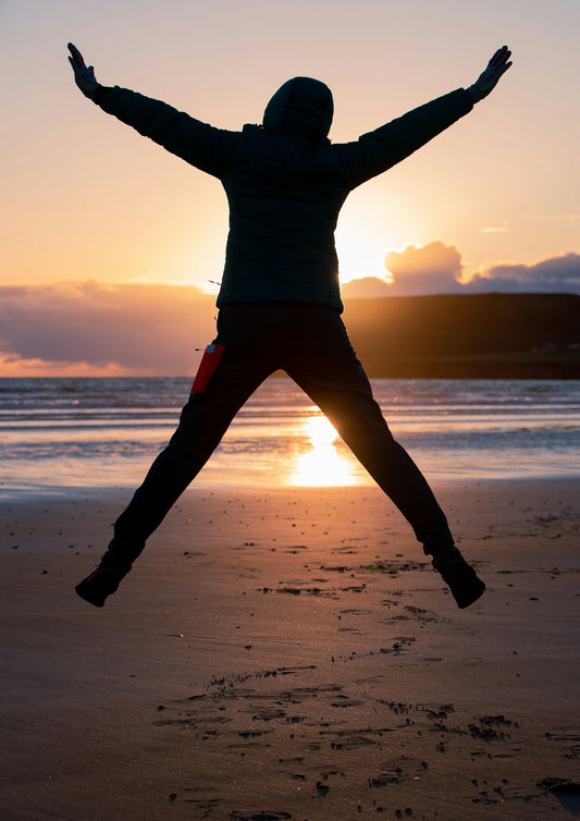 woman in black long sleeve shirt and red pants standing on beach during sunset