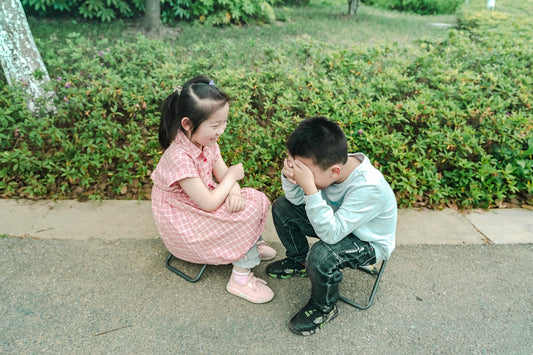 a boy and a girl sitting on a bench