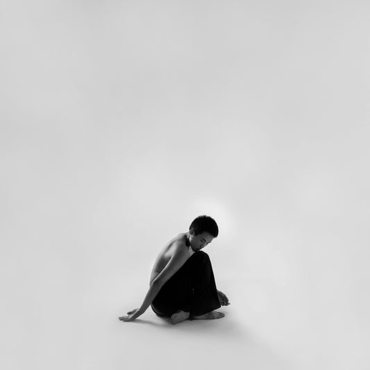 man in black and white hoodie sitting on white surface