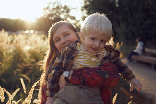 boy in red and black plaid dress shirt carrying girl in brown jacket