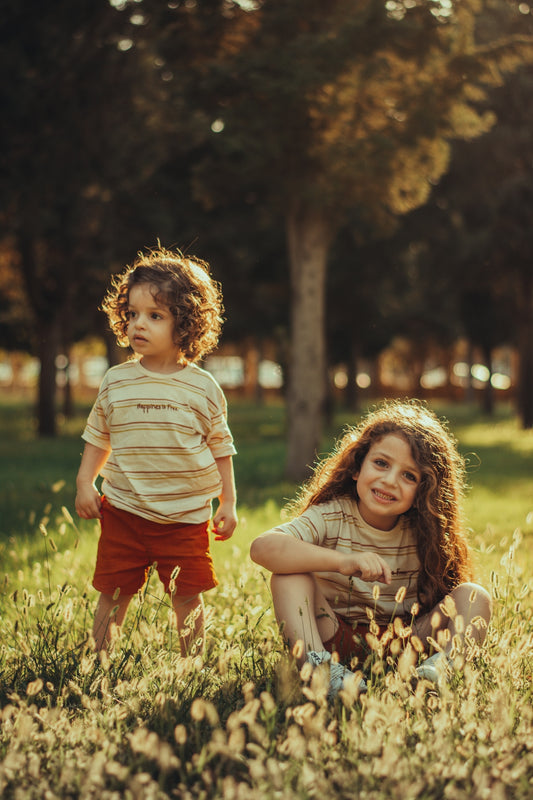 a young girl and a young boy are sitting in the grass