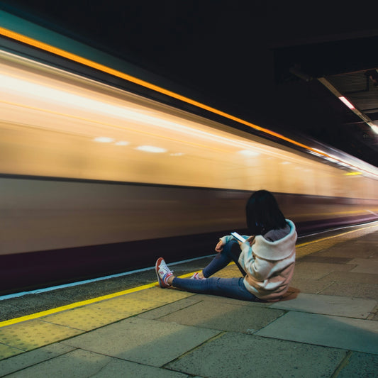 a woman sitting on the ground in front of a train