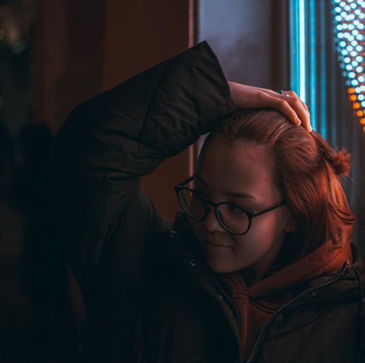 a woman with red hair wearing glasses and a black jacket