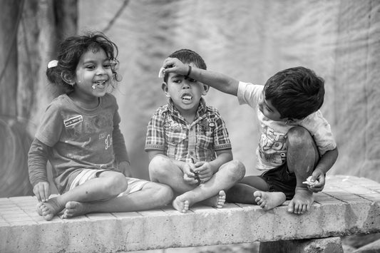 a group of children sitting on top of a cement wall