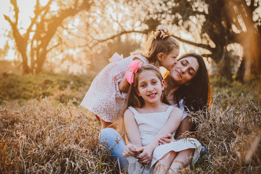 a family of three sitting in a field of tall grass