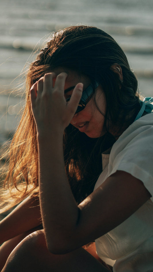 a woman sitting on the beach looking at her cell phone