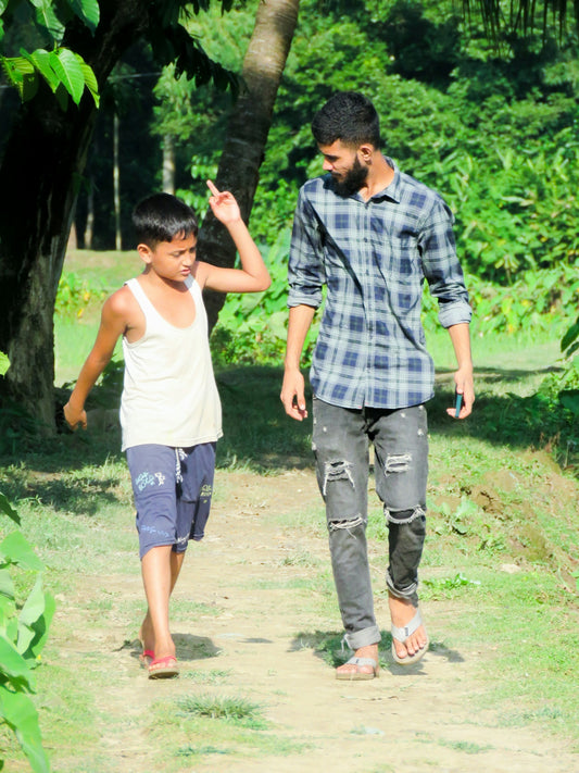 a man and a boy walking down a dirt road