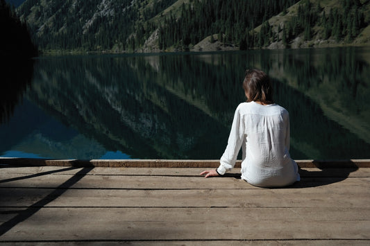 a woman sitting on a dock looking at a lake