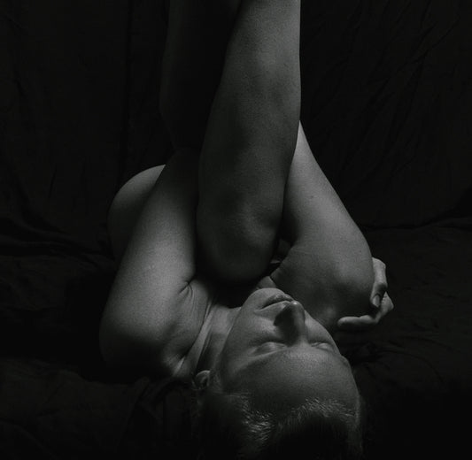 a naked man laying on his back on a bed