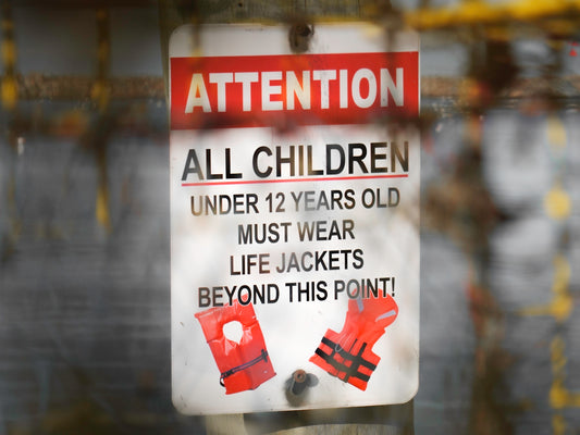 a sign on a pole that says attention all children under 12 years old must wear
