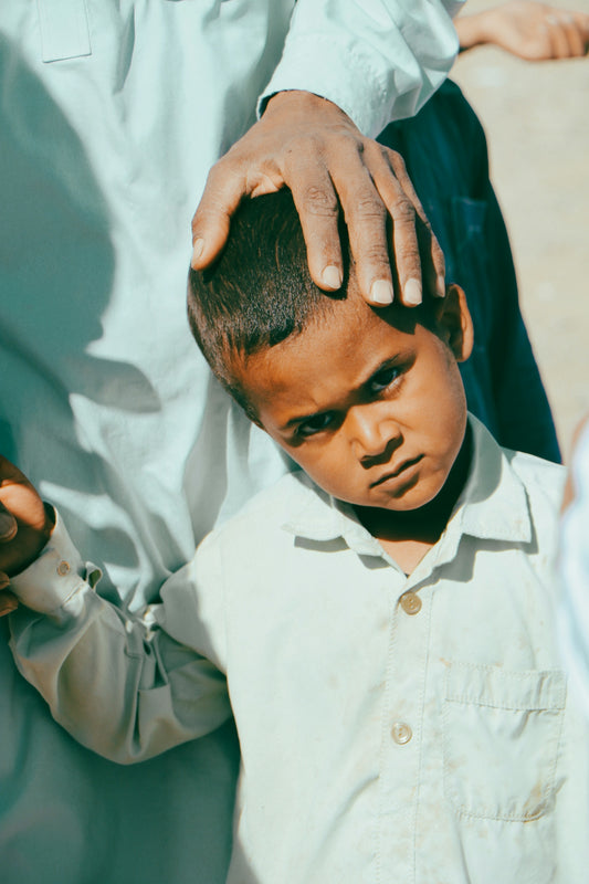 a young boy holding his hand up to his head