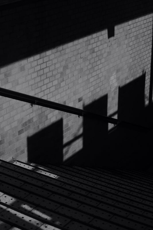 a black and white photo of a brick wall with a metal bar