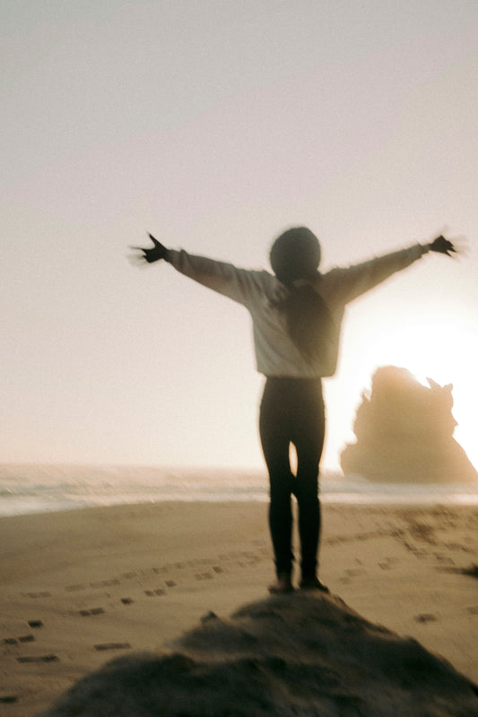 a person standing on a beach with their arms outstretched