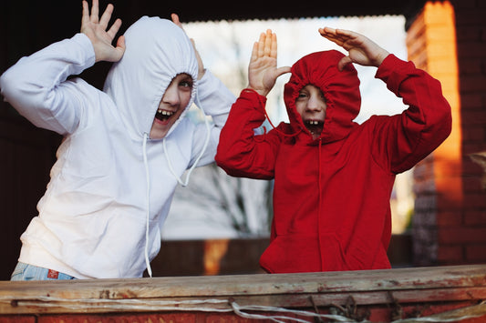 a couple of men wearing hoods and holding their hands up