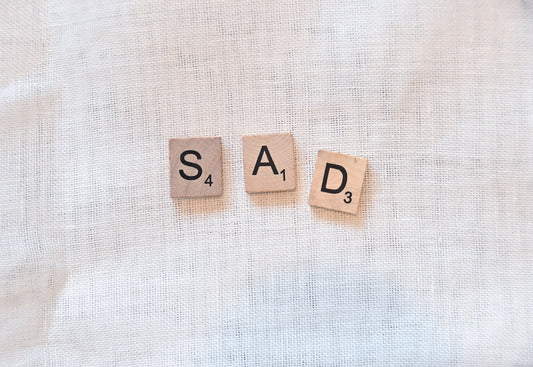 scrabble pieces spelling out sad