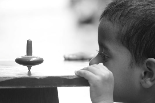 a young boy is looking at an object on a table